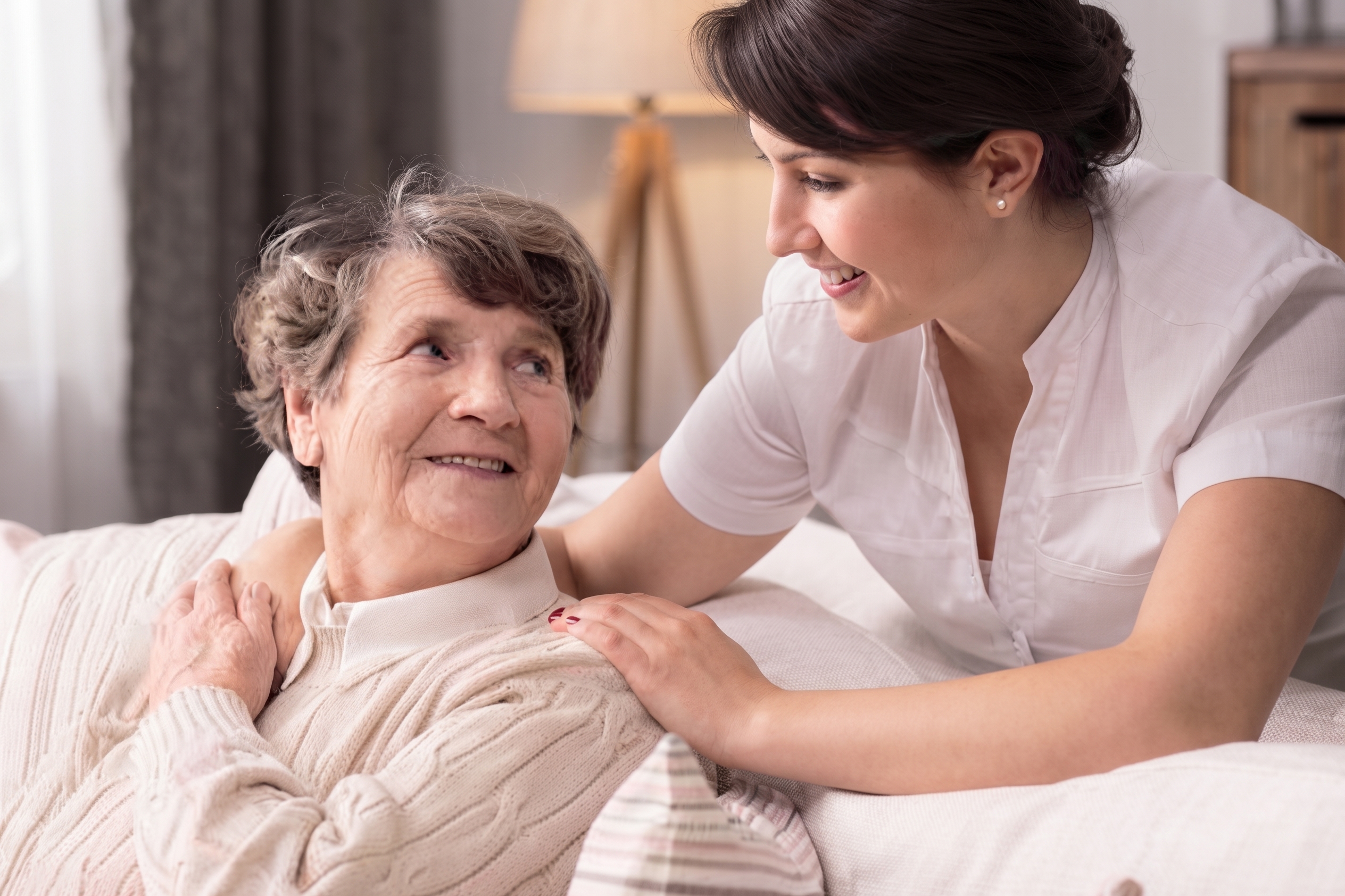 A carer smiling warmly with an elderly client at home